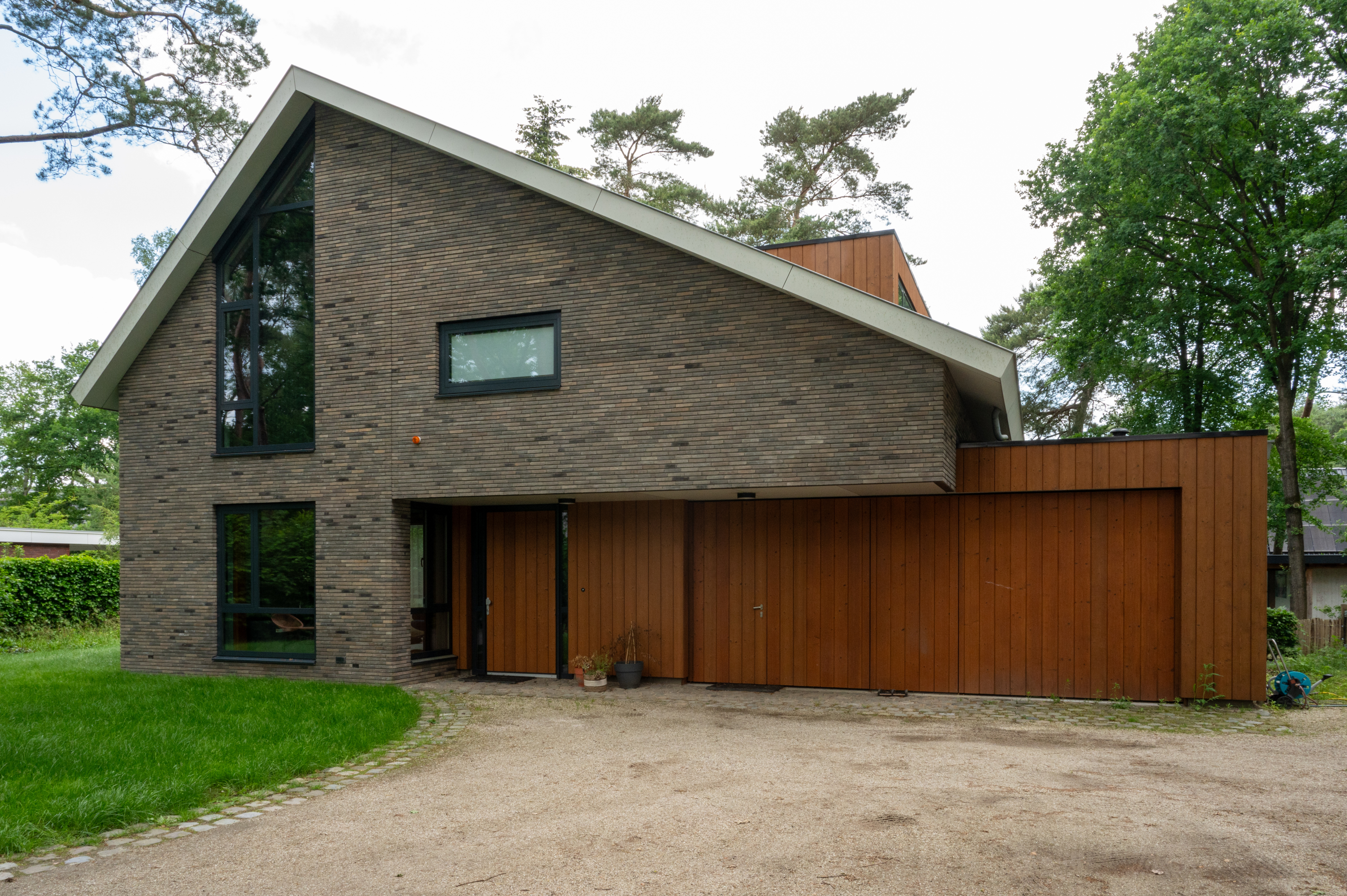 voorkant vrijstaande woning in bos met combinatie van steen en hout bekleed gebouwd door bouwbedrijf w bouw
